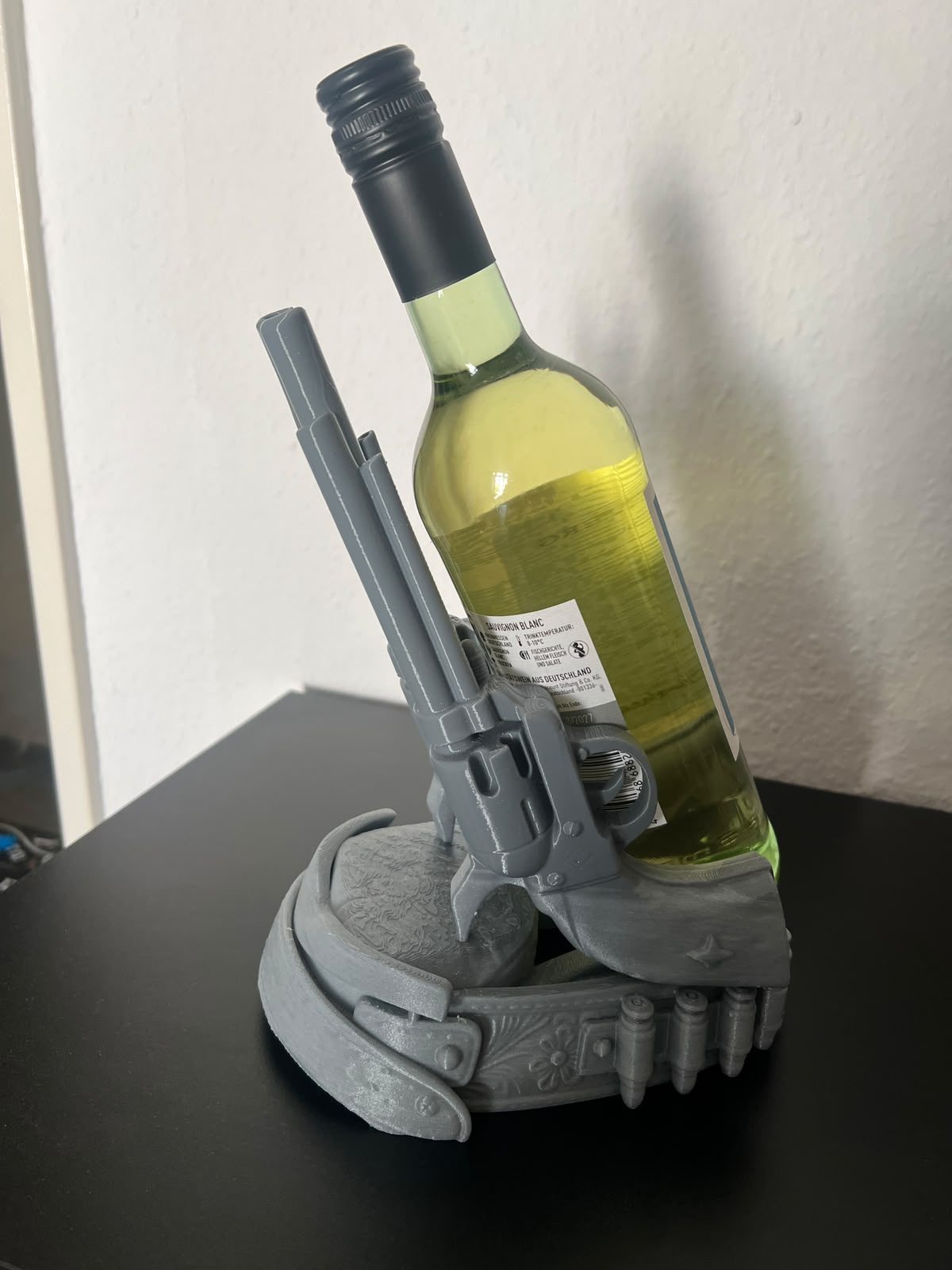 Suport gri pentru sticla de vin, decorat cu revolver si cartuse